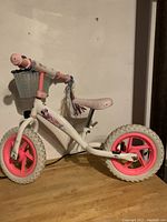 Side view of the kids balance bike showing white metal frame, pink wheels, and Mickey Mouse decals.