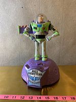 Front view of Buzz Lightyear figure standing on purple moon-like base with Buzz Lightyear label.