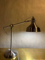 Full view of the stainless steel adjustable desk lamp with conical shade and weighted base