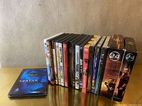 Photo shows a collection of DVDs and BluRay discs including a prominent Avatar BluRay case and two boxed sets of the TV series '24'.