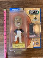 Vince Carter bobblehead figure in black and white warm-up outfit, inside original Upper Deck Play Makers All-Star Warm Up Edition packaging.
