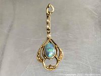 Close-up of the pendant showing the opal center and surrounding gold design with pearls on the bail chain.