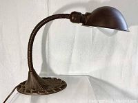 Photo of full desk lamp showing flexible gooseneck, dome shade and decorative cast base with leaf motifs.