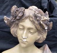 Close-up of the face and floral crown showing detailing and paint chipping.