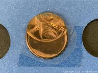 Close-up of 1925 Lincoln Wheat Cent with mis-strike/deformed design taped in holder.