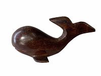 Side view of the dark wooden whale figurine showing smooth curves and detailed tail fin