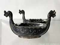 Side view of two Viking ship salt cellars showing dragon head prow and shield decoration