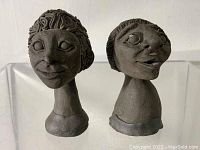 Pair of small sculpted ceramic busts photographed from front showing facial details.