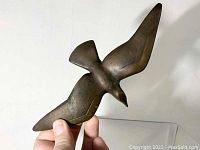 Side view of the cast bronze seagull sculpture showing the flowing form and patina of the bronze.