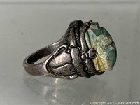 Side view of sterling silver scarab ring showing carved stone and silver scarab design on side.