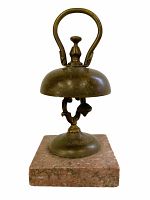 Front view of the antique bell showing brass bell and stone base.