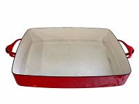 Rectangular red and white enamel casserole dish with visible minor wear on the glaze inside, shown from an angled top side view.