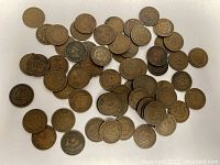 65 Indian Head pennies laid flat on white background showing obverse and reverse sides