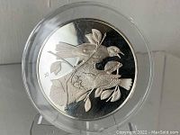 Front view of sterling silver medallion with relief of Baltimore Oriole birds on branches