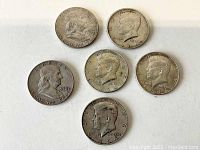 Front side of six half dollar coins showing Kennedy and Franklin profiles and years on the coins
