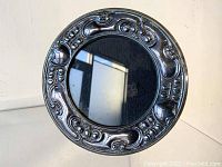 Front view of round silver frame showing detailed Art Nouveau motifs around the circular border