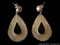 Pair of vintage sterling silver Taxco earrings with black teardrop inlay shown on black background.