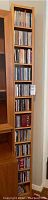 Full view of the tall laminated wooden CD cabinet filled with CDs