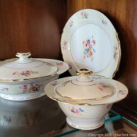 Photo showing one serving plate and two lidded bowls with floral and gold trim detailing.