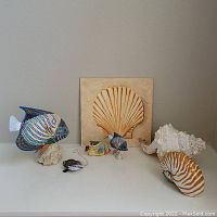 Display of all fish figurines, large seashells, and the signed seashell print together on a white surface.