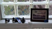 Framed lighthouse photo and three painted wood duck figurines displayed on a windowsill.