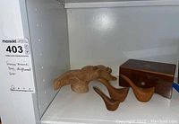 Shelf with wooden music box and three driftwood figurines including a dolphin and two ducks.