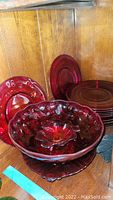 Red glassware plates and large serving bowl with textured interior and Amberina base on shelf.