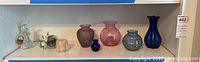 Shelf with five glass vases from 2 to 7 inches, clear rabbit figurine, small candleholder, and glass plant container