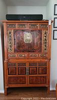 Full frontal view of vintage Asian carved wood cabinet on chest with brass hardware, two sections with drawers and doors, showing wood finish and design.
