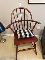 Front view of the wood vintage chair showing spindle backrest, armrests, and black and white checkered cushion on the seat.