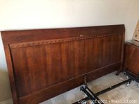 Wooden headboard with dark brown finish and carved trim detail.