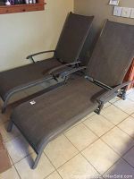 Two grey mesh sling lounge chairs side by side showing metal frames and seats