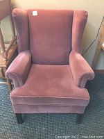 Front view of dusty rose wingback chair showing upholstery and armrests.