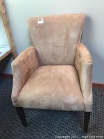 Front view of light brown suede arm chair with padded seat, arms, and high backrest.