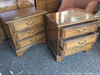 Two wooden nightstands with three drawers each, brass hardware, medium brown finish, slight finish wear seen on drawer fronts and edges.