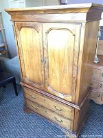 Front view of a wooden high boy cabinet with two doors and two drawers, showing overall shape and condition.