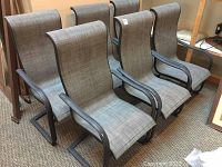 Six gray nylon mesh fabric patio chairs with black metal frames arranged in two rows indoors.