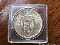 Close-up photo of the 1944 Netherlands 2 1/2 guilder silver coin in protective casing showing the crowned shield and denomination.