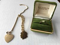 Three items laid out: two gold bracelets and ring in green velvet box