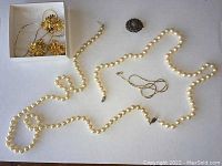 Photo shows gold tone pendant with matching clip-on earrings in a box, long and short faux pearl strands, and small round vintage silver brooch with red coral beads.