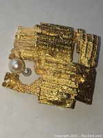 Front view of brooch showing textured irregular square form and two pearls