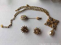 Entire lot laid out showing necklace chain with pendant, pair of clip-on earrings and stick pin