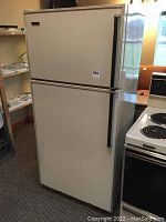 Full front and side view of the Westinghouse refrigerator showing white color and black handles next to a white stove.