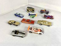 Top view of the 11 die-cast Hot Wheels vehicles showing various car models and one plane with orange propellers.
