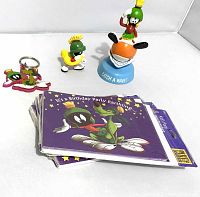 The lot displayed: stamped keychain, small Marvin figure with innertube, figurine statue 'Catch A Wave' statuette, and sealed birthday party invitations set.