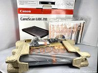 Canon CanoScan LiDE210 box with scanner wrapped in packaging and accessories on top