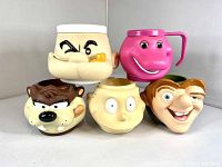 Front view of five plastic character mugs arranged in two rows, faces visible, showing Popeye, Barney, Tasmanian Devil, Hunchback of Notre Dame, and Rugrat characters.
