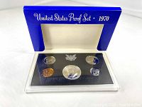 Opened proof set case showing the 5 coins with protective transparent cover and blue cardboard outer packaging.