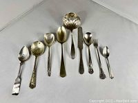 Set of 8 various vintage silver plated utensils, spoons, fork, butter knife, and ladle shown side by side