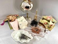 Image showing the full assortment of vintage vanity items including handkerchiefs, oval tabletop mirror, hair pins, clips, comb, glass perfume bottle, and decorative boxes.